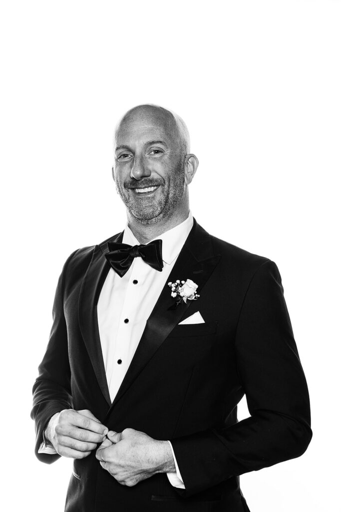 man buttoning his suit smiling in glam booth 