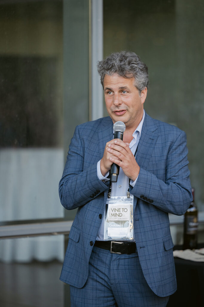 Speaker addressing attendees at the Vine to Mind Symposium wearing a Vine to Mind badge.